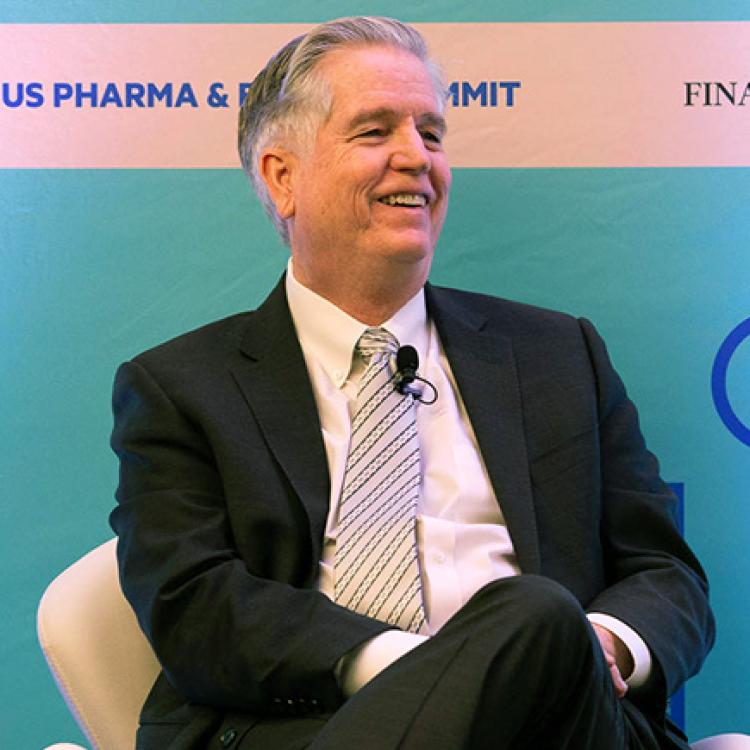 man in suit sitting in front of blue backdrop