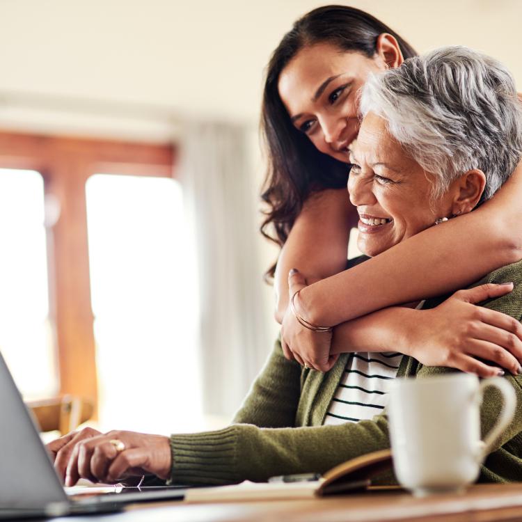 daughter hugging mom at computer