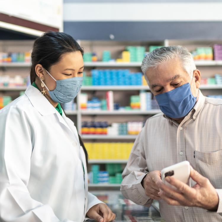 Pharmacist talking to patient, wearing masks