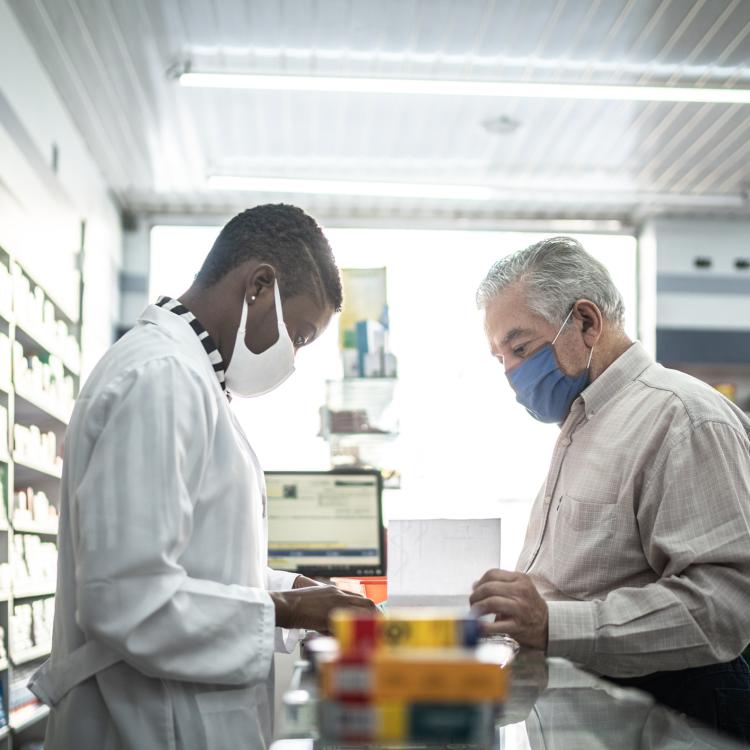 Pharmacist helping patient at a counter.