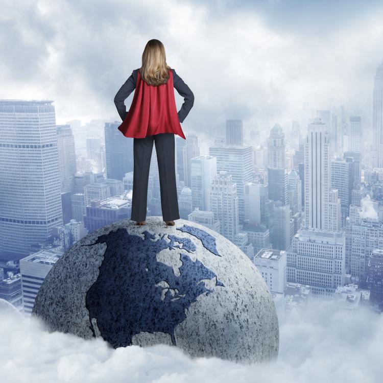 Women with superhero cape standing on globe