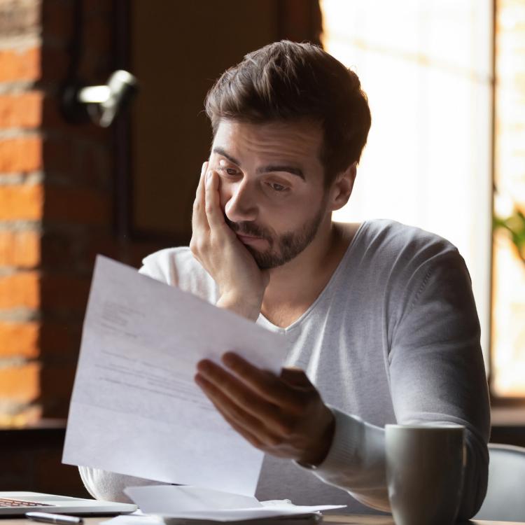 Concerned man, reading a letter in front of his laptop