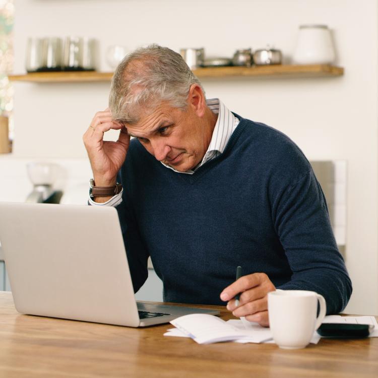 Man evaluating insurance plan options at his laptop