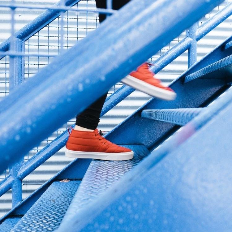 Person in orange sneakers climbing steps